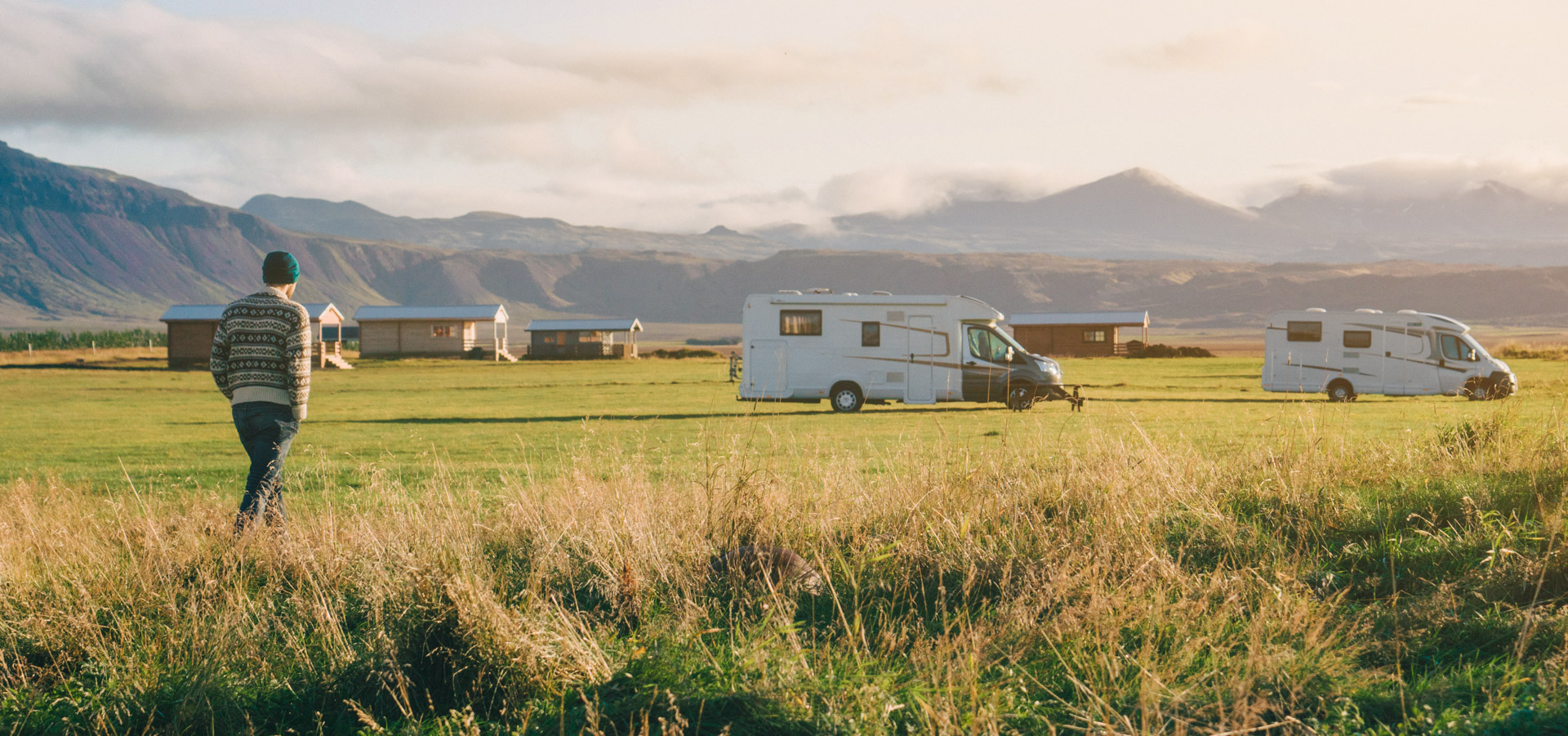Young Caucasian man walking in camping near camping vans in Iceland