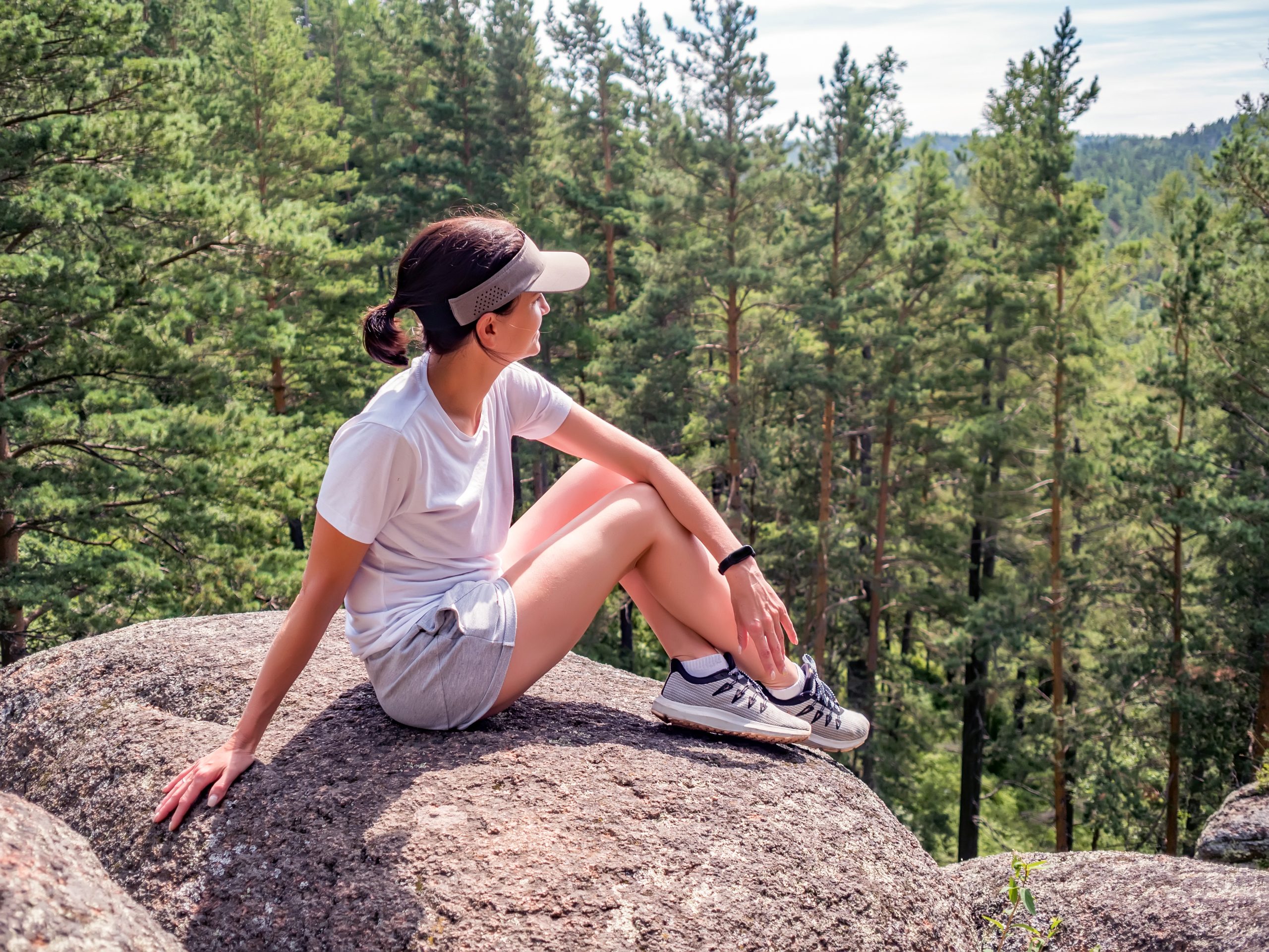 Young girl is sitting alone on the rock. Solo travel, peace of mind. Hiking.
